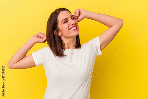 Young caucasian woman isolated on yellow background celebrating a special day, jumps and raise arms with energy.