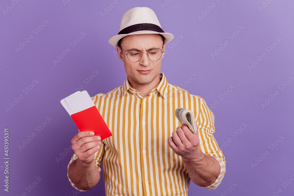 Portrait of tourist uncertain guy hold tickets cash banknote think payment on purple background