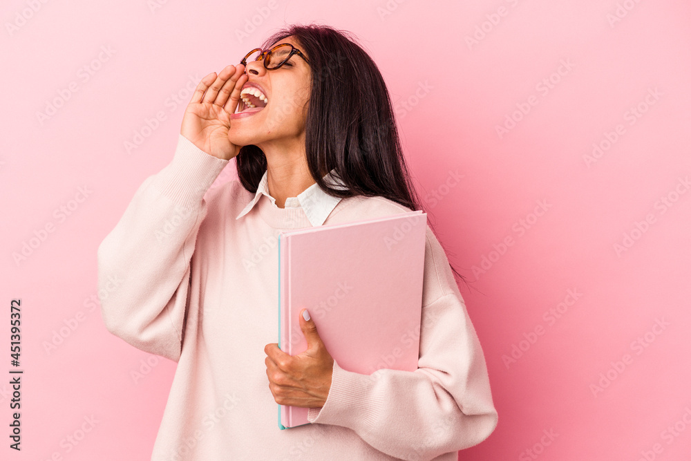Young student latin woman isolated on pink background shouting and holding palm near opened mouth. Young student latin woman isolated on pink background shouting and holding palm near opened mouth.