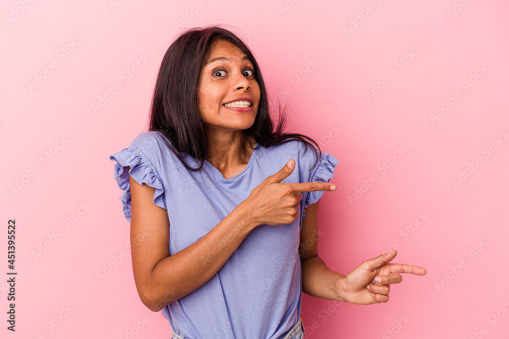 Young latin woman isolated on pink background shocked pointing with index fingers to a copy space. Young latin woman isolated on pink background shocked pointing with index fingers to a copy space.
