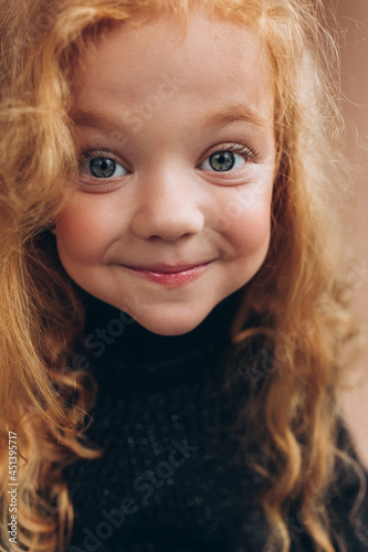 Adorable joyful girl. Funny curly red headed child in studio. Childhood, funny baby girl concept