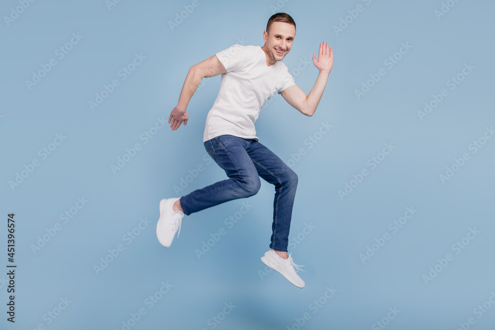 Full body profile side photo of cheerful brown haired attractive man jumping running waving hello isolated over blue color background