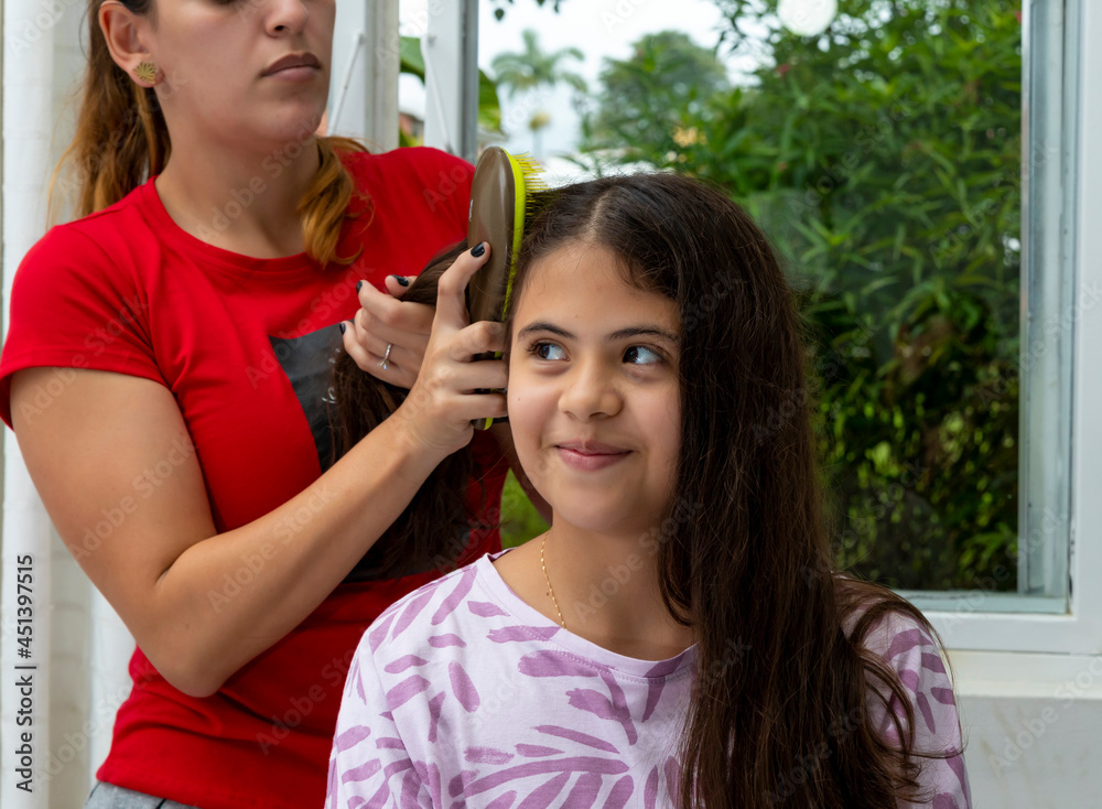 mom combing her daughter's hair in the bedroom mom combing her daughter's hair in the bedroom