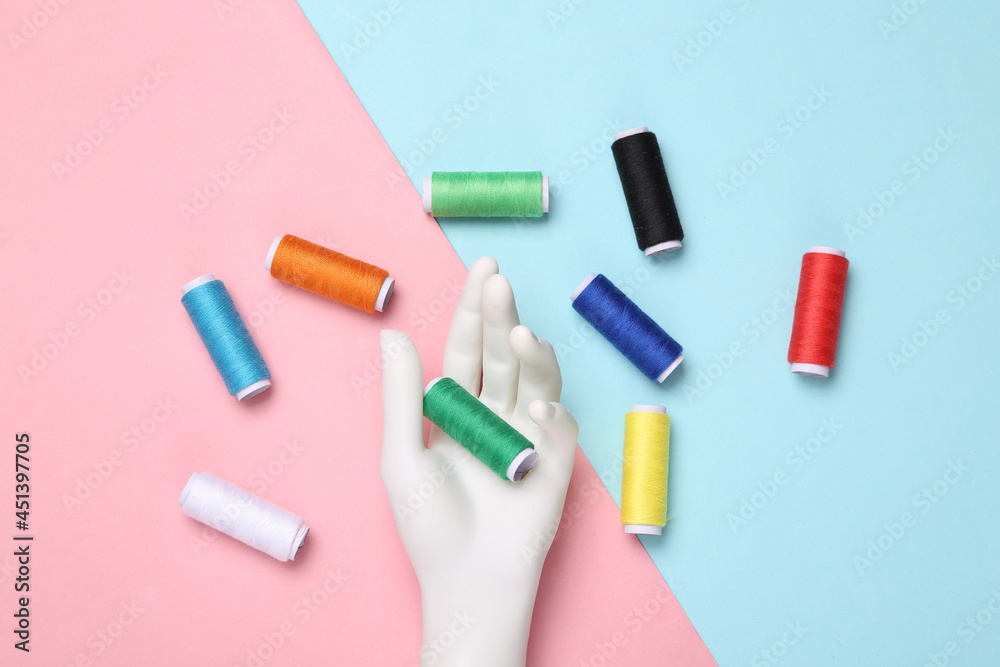 Hand holding Skeins of colored thread on blue-pink pastel background Hand holding Skeins of colored thread on blue-pink pastel background
