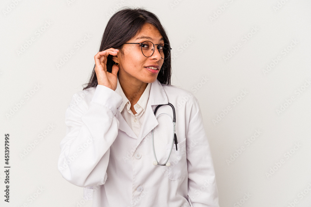 Young doctor latin woman isolated on white background trying to listening a gossip. Young doctor latin woman isolated on white background trying to listening a gossip.