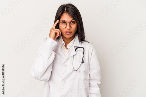 Young doctor latin woman isolated on white background pointing temple with finger, thinking, focused on a task.