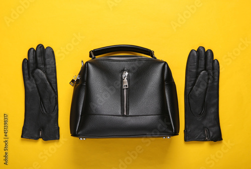 Leather bag and gloves on yellow background. Top view