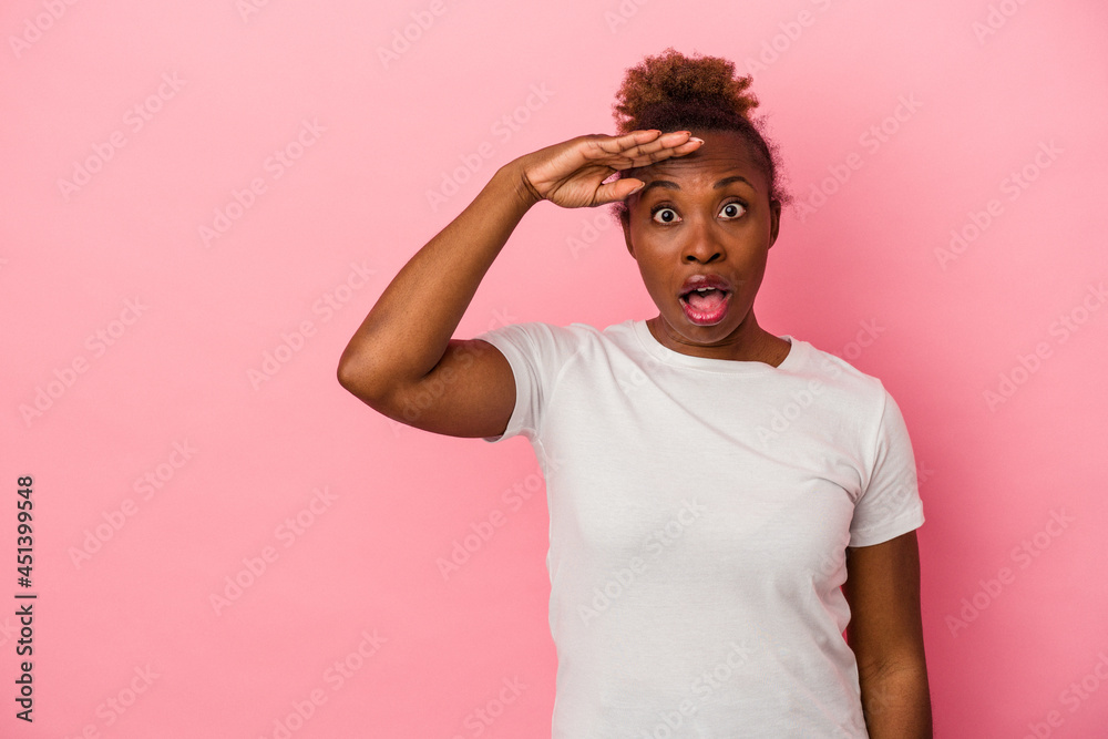 Young african american woman isolated on pink background shouts loud, keeps eyes opened and hands tense. Young african american woman isolated on pink background shouts loud, keeps eyes opened and hands tense.