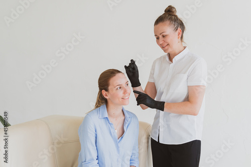 Eyebrow master, beautician models the eyebrows of a young woman