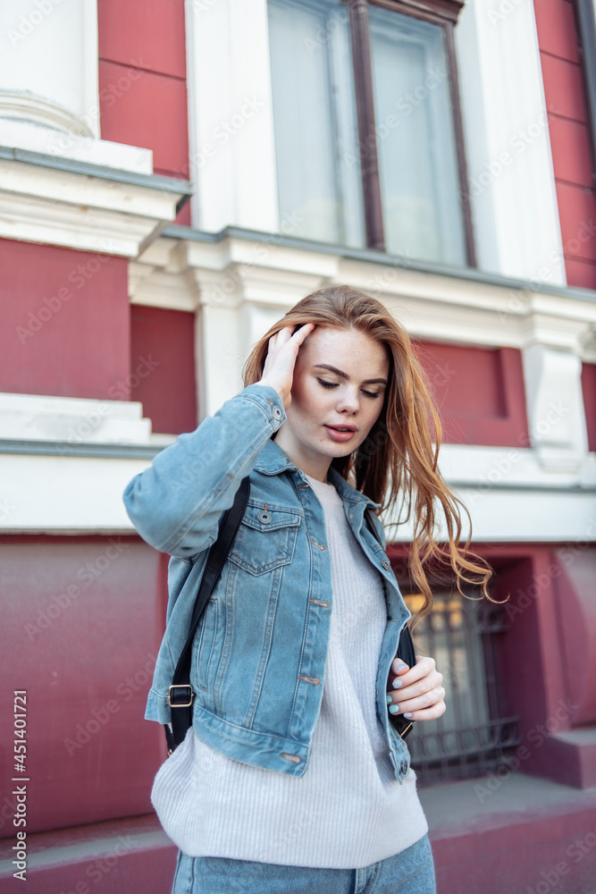Stylish sexy woman in denim clothes and backpack in city