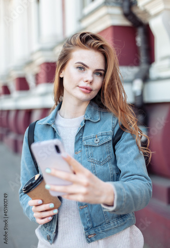 Young pretty woman using smartphone and lokk at camera in the city photo