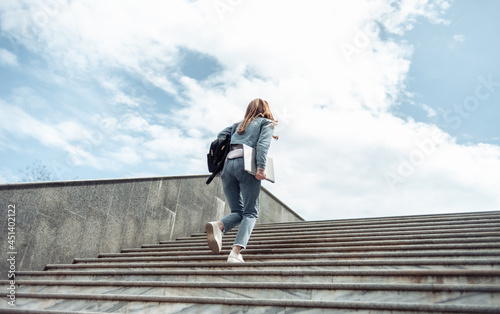 Young woman student climbs the stairs up photo