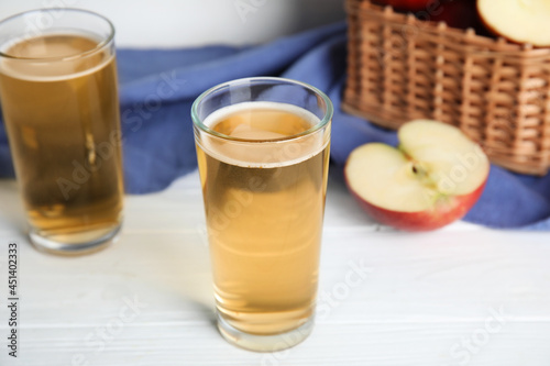 Glasses of delicious apple cider on white table