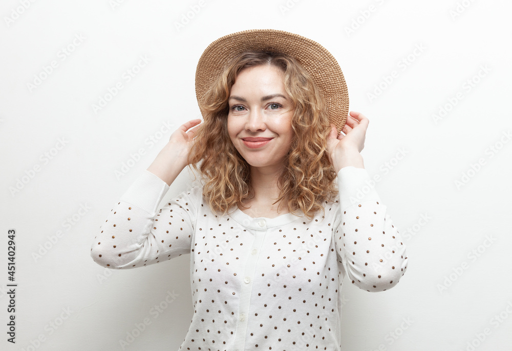 Portrait of cute smiling curly haired Caucasian woman in straw hat on white background Portrait of cute smiling curly haired Caucasian woman in straw hat on white background