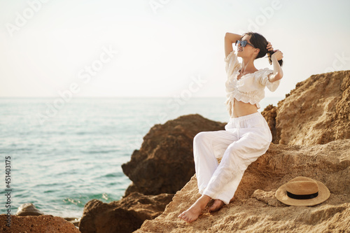 Woman traveler sitting near sea on cliff injoying view of sea and nature photo