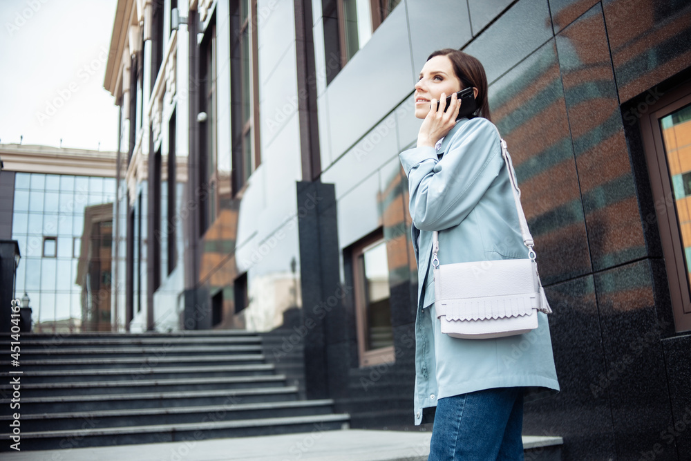 Fototapeta premium Cute business lady talking on the phone on the stairs. Modern lifestyle