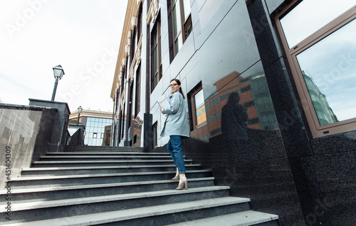 Modern business woman climbs the stairs near the business center. Lifestyle