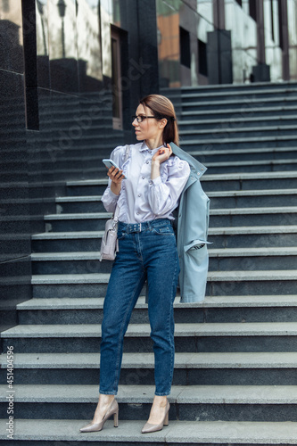 Modern business woman uses a smartphone while standing on the stairs © splitov27