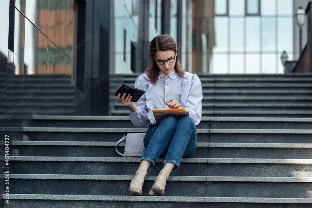 Modern business woman writes down important information while walking on the stairs