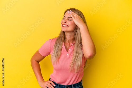 Young russian woman isolated on yellow background blink at the camera through fingers, embarrassed covering face.