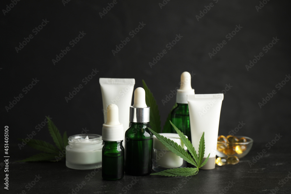 Composition with CBD oil, THC tincture and hemp leaves on black stone table