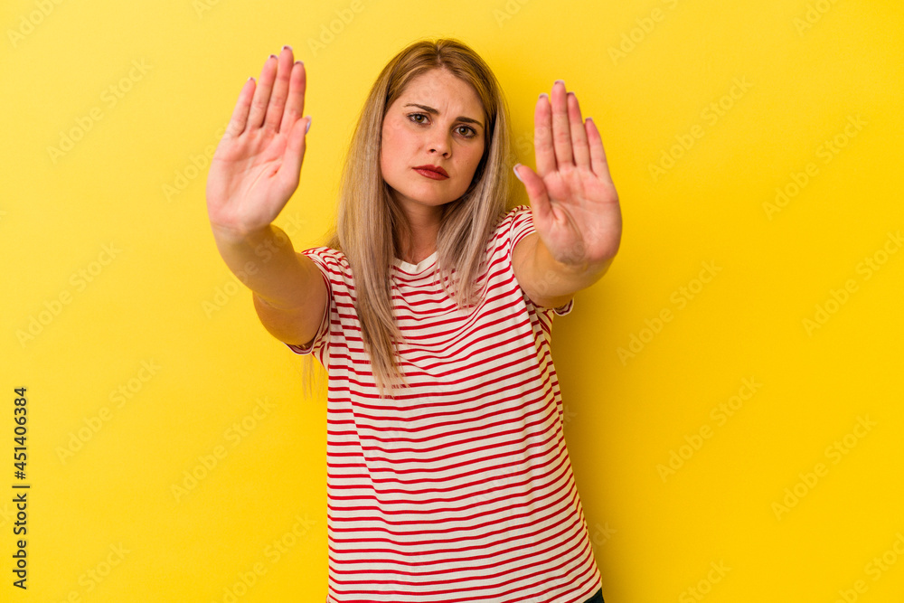 Young russian woman isolated on yellow background standing with outstretched hand showing stop sign, preventing you. Young russian woman isolated on yellow background standing with outstretched hand showing stop sign, preventing you.