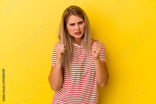 Young russian woman isolated on yellow background upset screaming with tense hands.