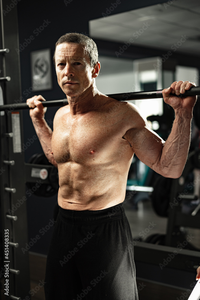 Senior man working out at the gym doing squats Senior man working out at the gym doing squats