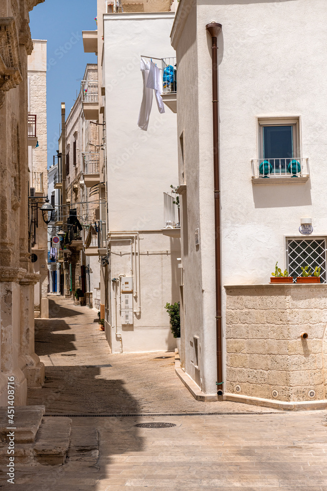 wąska uliczka miedzy kamienicami z białego kamienia, Monopoli, Puglia, Włochy  - obrazy, fototapety, plakaty 