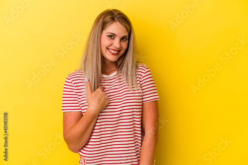 Young russian woman isolated on yellow background surprised pointing with finger, smiling broadly.