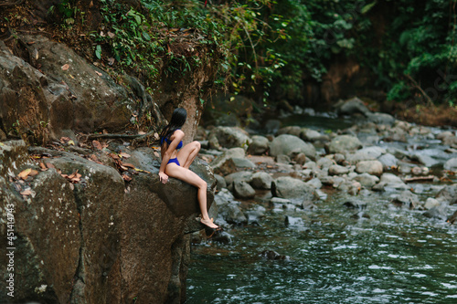 Woman sitting near river in forest photo