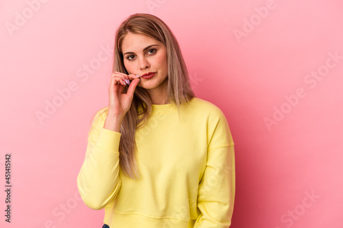 Young russian woman isolated on pink background with fingers on lips keeping a secret.