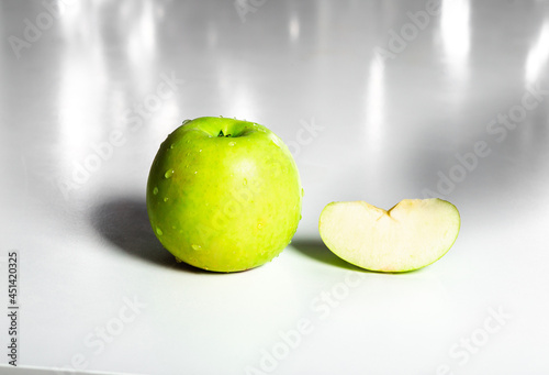 isolated green apple with dew drop and apple slice on white table