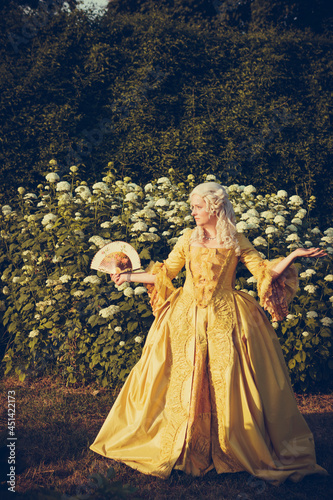 Portrait of blonde woman dressed in historical Baroque clothes with old fashion hairstyle, outdoors. Luxurious medieval dress