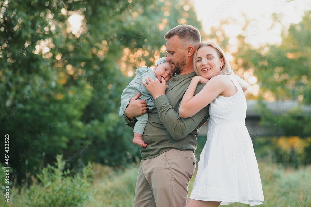 Young beautiful family with a little daughter hug, kiss and walk in nature at sunset. Photo of a family with a small child in nature. Young beautiful family with a little daughter hug, kiss and walk in nature at sunset. Photo of a family with a small child in nature.