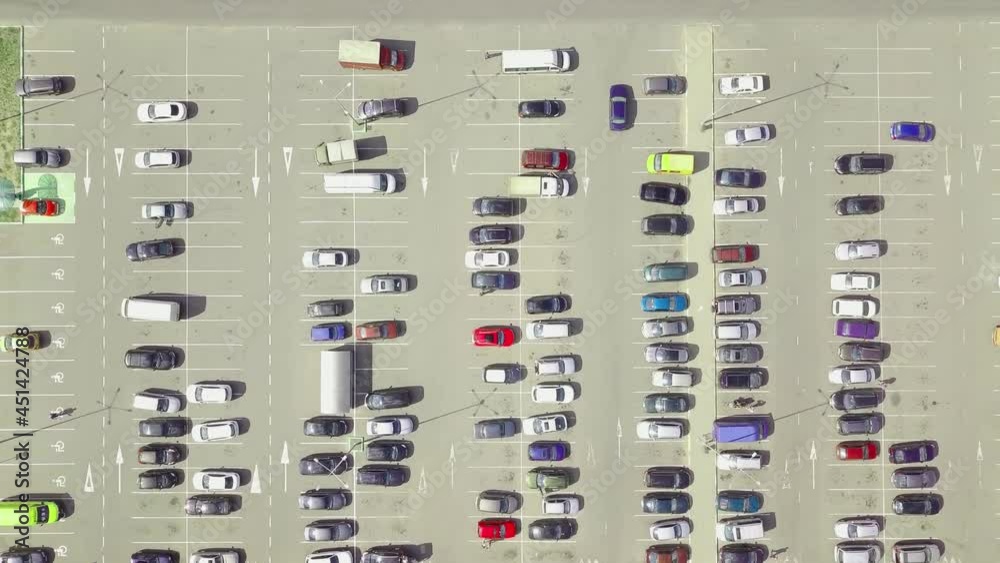 A bird's-eye view of parked cars in the parking lot near the shopping center. The camera is directed vertically downwards. Parking of cars in the open air. Summer.