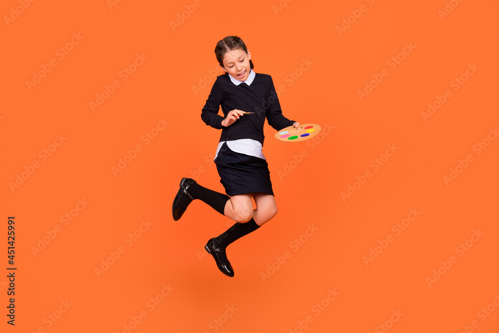 Full length body size view of pretty cheerful preteen girl jumping drawing design craft isolated over bright orange color background