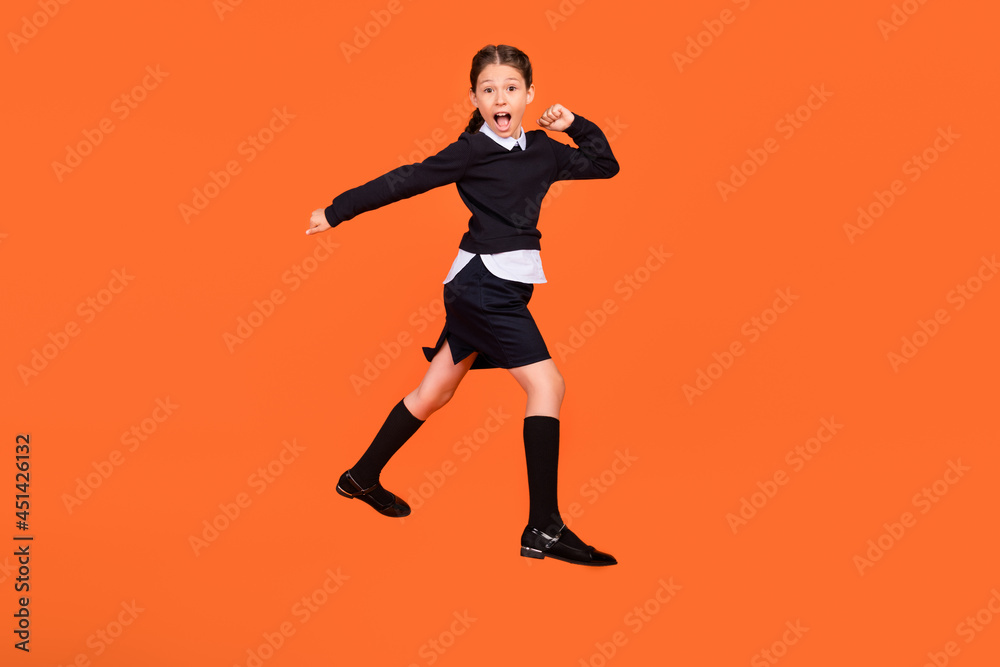 Full length photo of amazed shocked little girl jump up go walk empty space sale isolated on orange color background