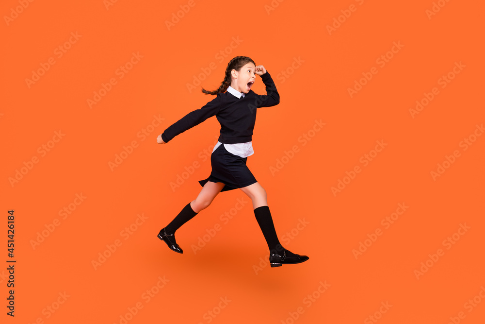 Full length body size view of pretty motivated cheery preteen girl jumping running isolated over bright orange color background