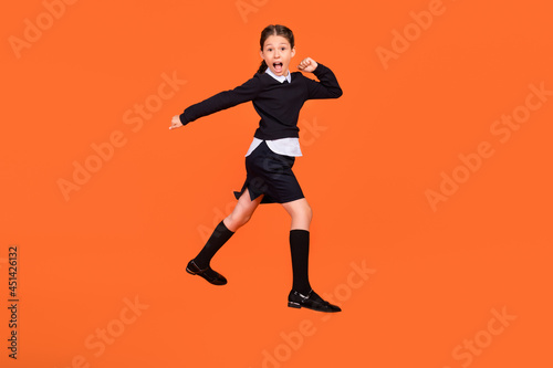 Full length photo of amazed shocked little girl jump up go walk empty space sale isolated on orange color background