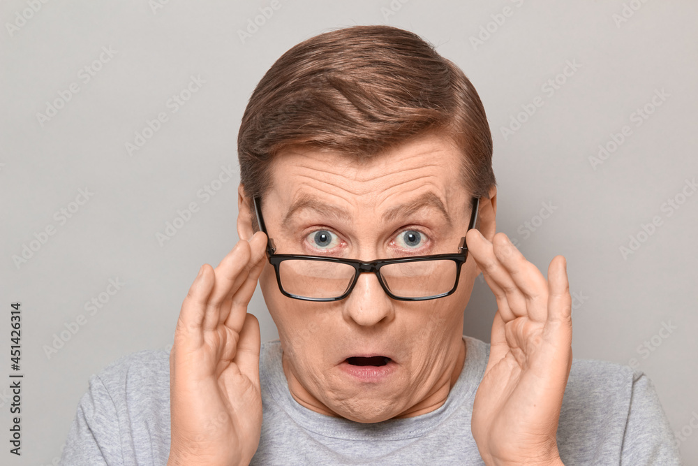 Portrait of shocked man peering over glasses at something unbelievable Portrait of shocked man peering over glasses at something unbelievable