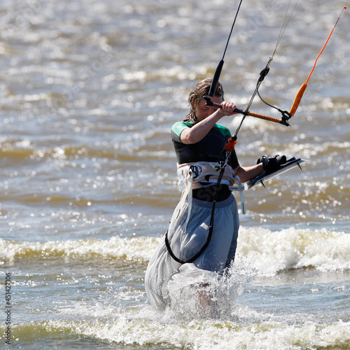 Kiter girl in a long skirt goes to shore after kiteboarding