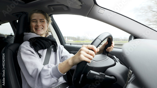 Young woman with natural look driving a passenger car on a German highway. The young woman shows various emotional reactions to the traffic event. © Juergen Nowak