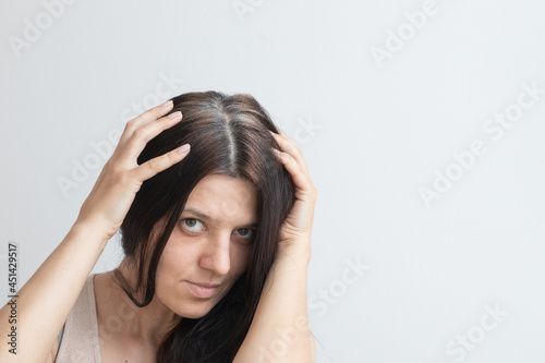 Fragments of gray hair on the head of a young woman. Early gray hair concept. Gray hair color and structure. Copy space