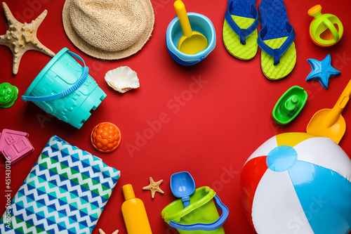 Frame of beach ball and sand toys on red background, flat lay. Space for text