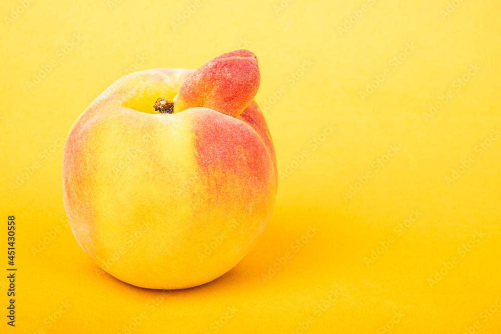 peach sexy fruit of an unusual shape with copy space on yellow background.  foto de Stock | Adobe Stock
