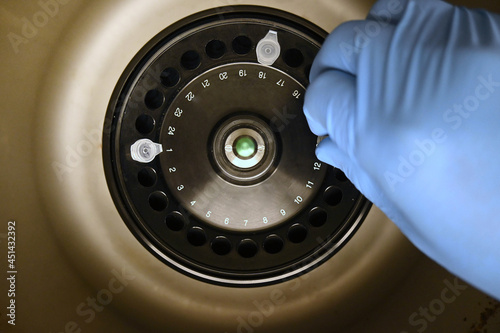 Overhead shot of researcher's hand placing tube in laboratory centrifuge