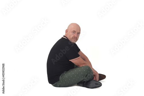 side view of man sitting on floor looking at camera on white backgound