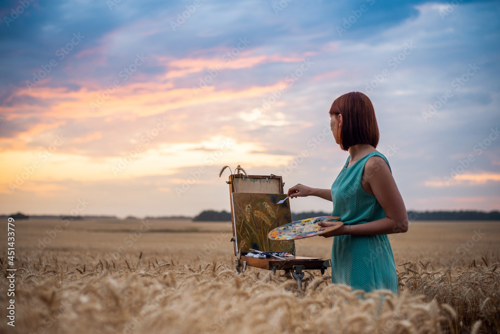 Artist at work. Beautiful evening in the field of ripe rye and inspired artist making final touches to her masterpiece painting