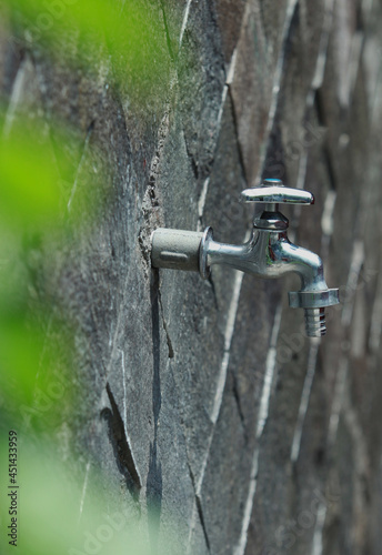 Close up of faucet with stone wall background